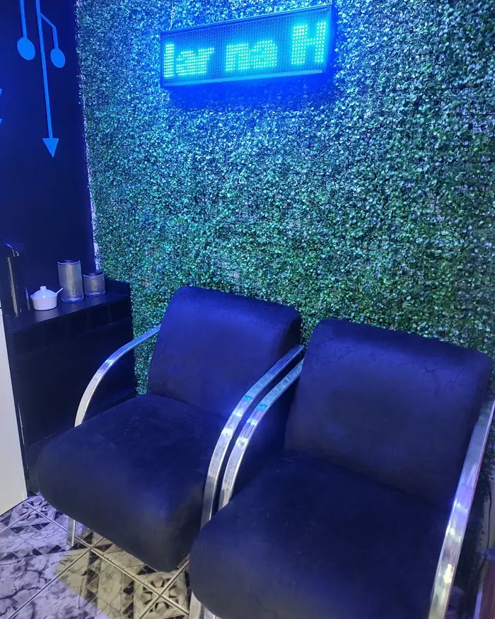 Sala de espera da loja, com poltronas azuis e parede verde